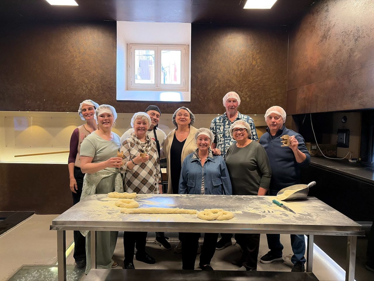 The group in hairnets around the floury table with their hand-shaped loaves