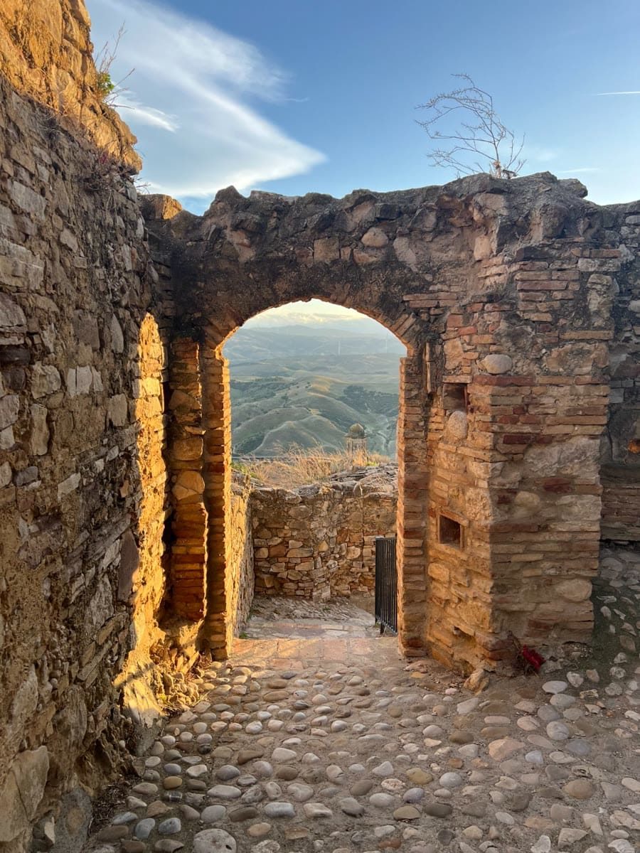 A ruined stone archway in Craco framing the Basilicata hills